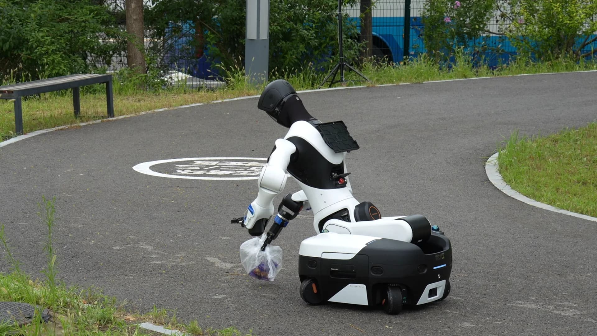 AGIBOT humanoid robot collecting a bag of litter from the park course