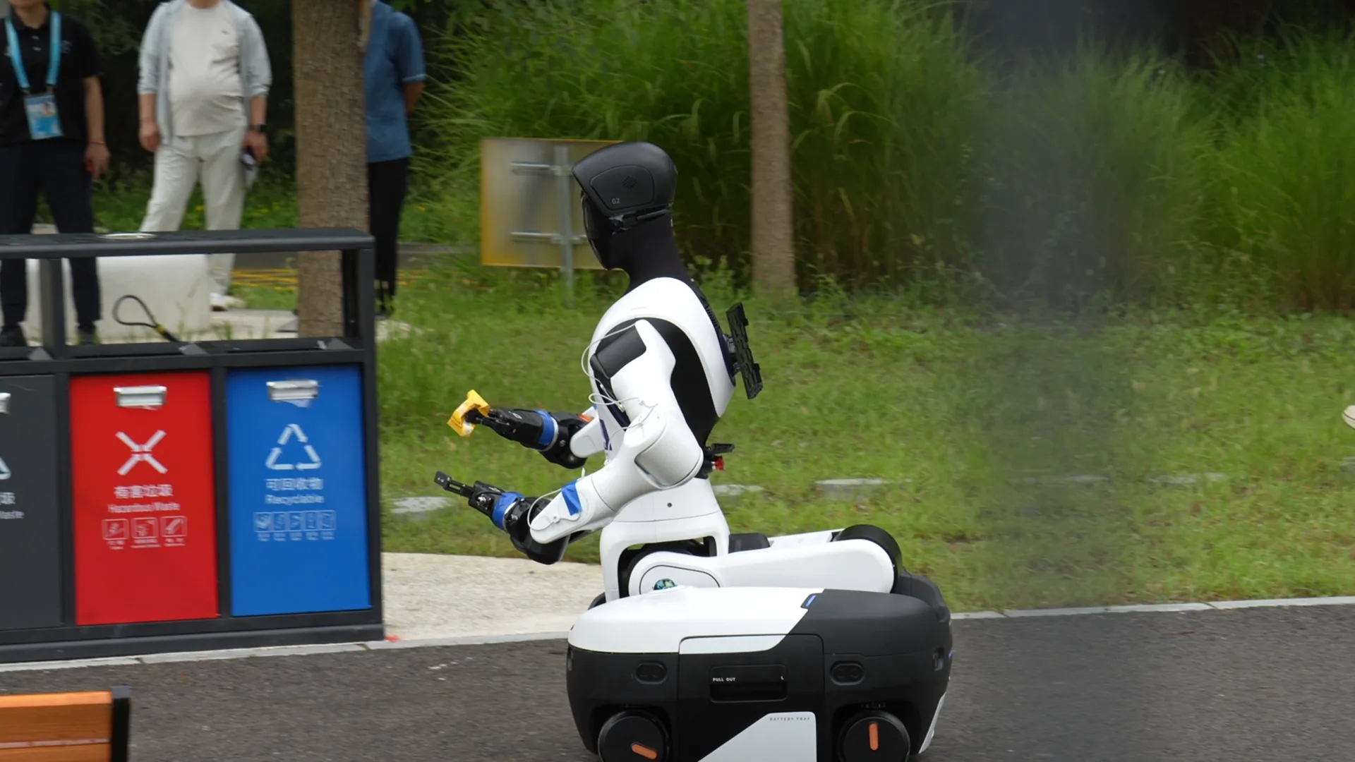 AGIBOT humanoid robot carrying an item beside the competition waste station